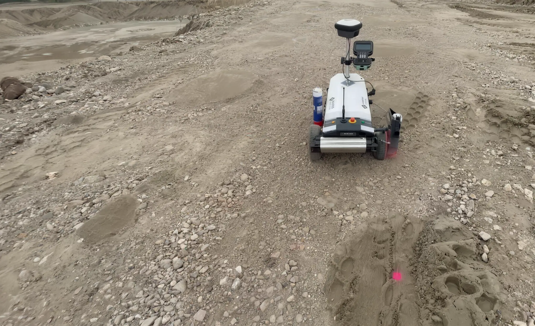 Onze robotplotter rijdt over het bouwterrein, met een vers gespoten roze uitzetstip in het rijspoor
